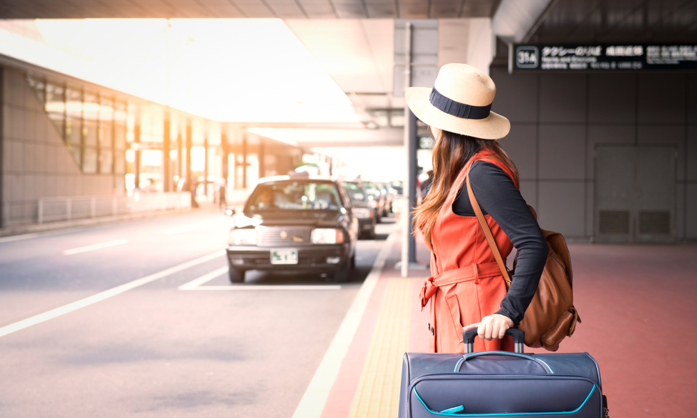 How to find cheap last minute flights: Tourist is waiting a taxi in front of Tokyo airport in Japan.