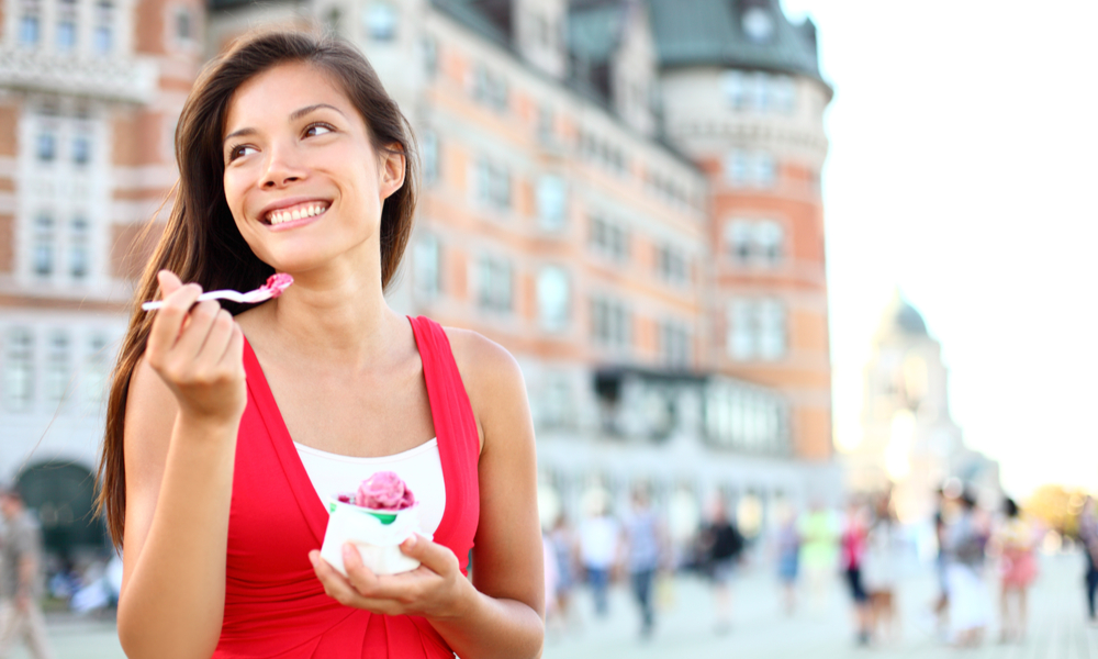 Top Domestic Destinations in Canada: Tourist woman eating ice cream in Quebec City in front of chateau frontenac in Quebec City, Quebec, Canada.