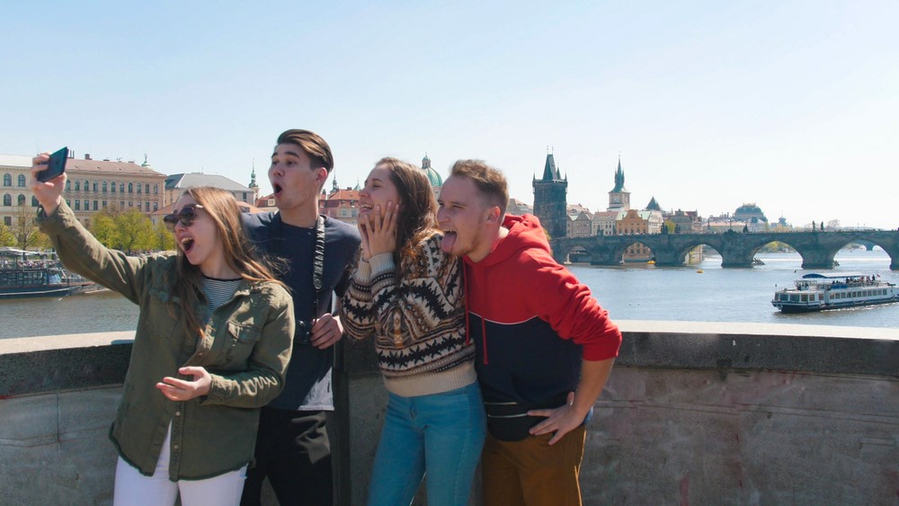 Company of friends stand on the bridge and take a selfie in the Czechia, Prague