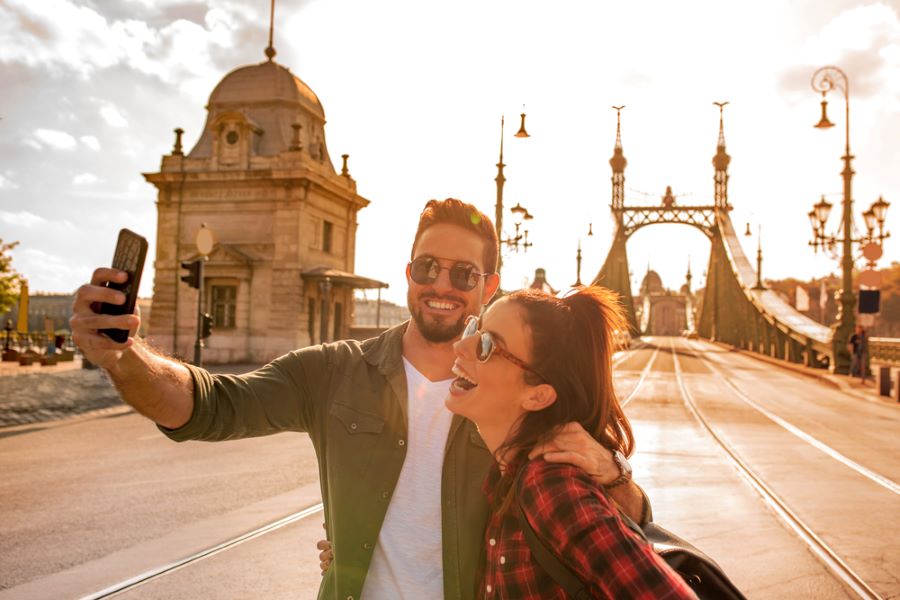 A happy couple taking a selfie in front of the famous liberty bridge during summer in Budapest in Hungary..