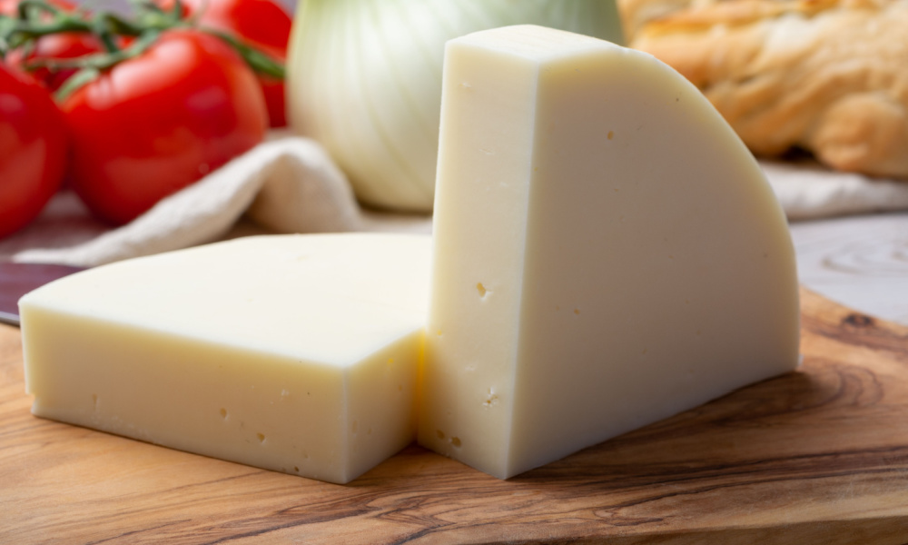 Italian cheese, Provolone dolce cow cheese from Cremona served with olive bread and tomatoes close up