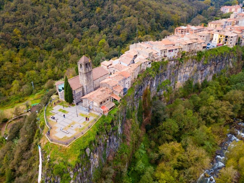 Picturesque forest landscape with medieval village of Castellfollit de la Roca on rocky cliff, Spain..