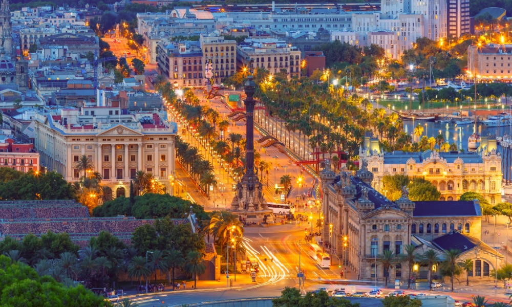 Aerial view over square Portal de la pau, and Port Vell marina and Columbus Monument at night in Barcelona,