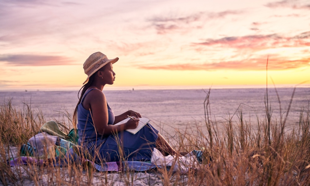 Woman writing in journal on the beach